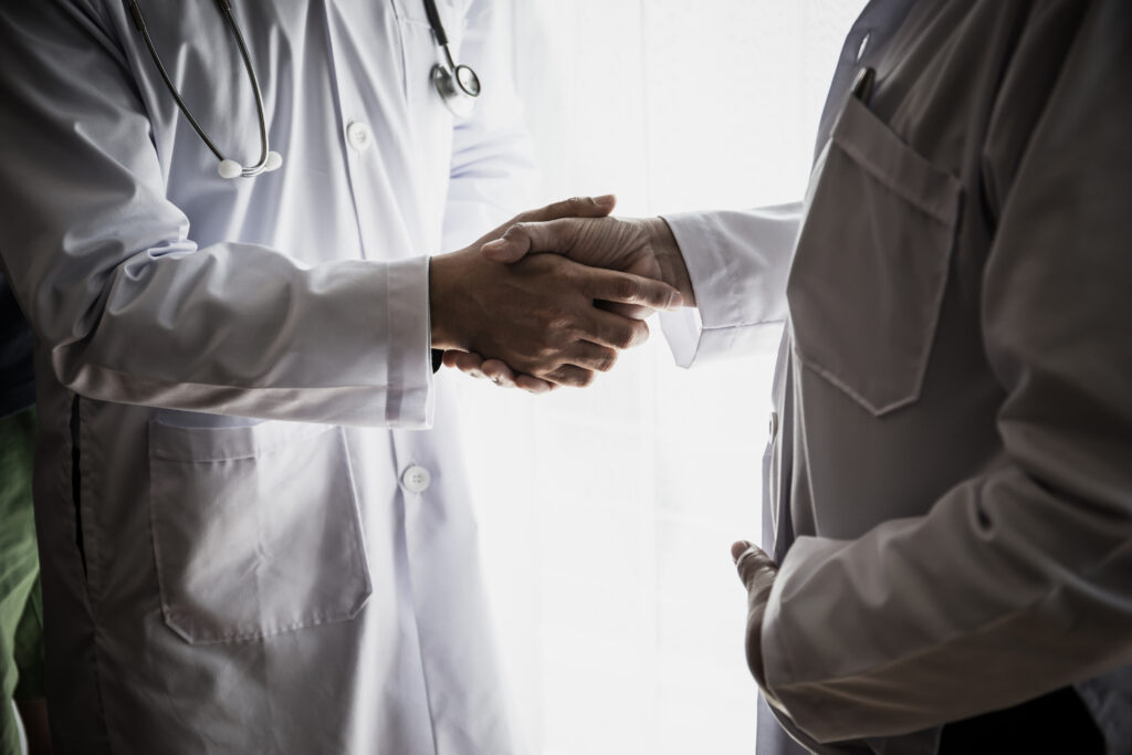 Close up of doctor giving a handshake to his partner, successfully.